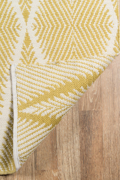 Yellow and white geometric woven rug with a starburst pattern, folded corner on a wood floor.
