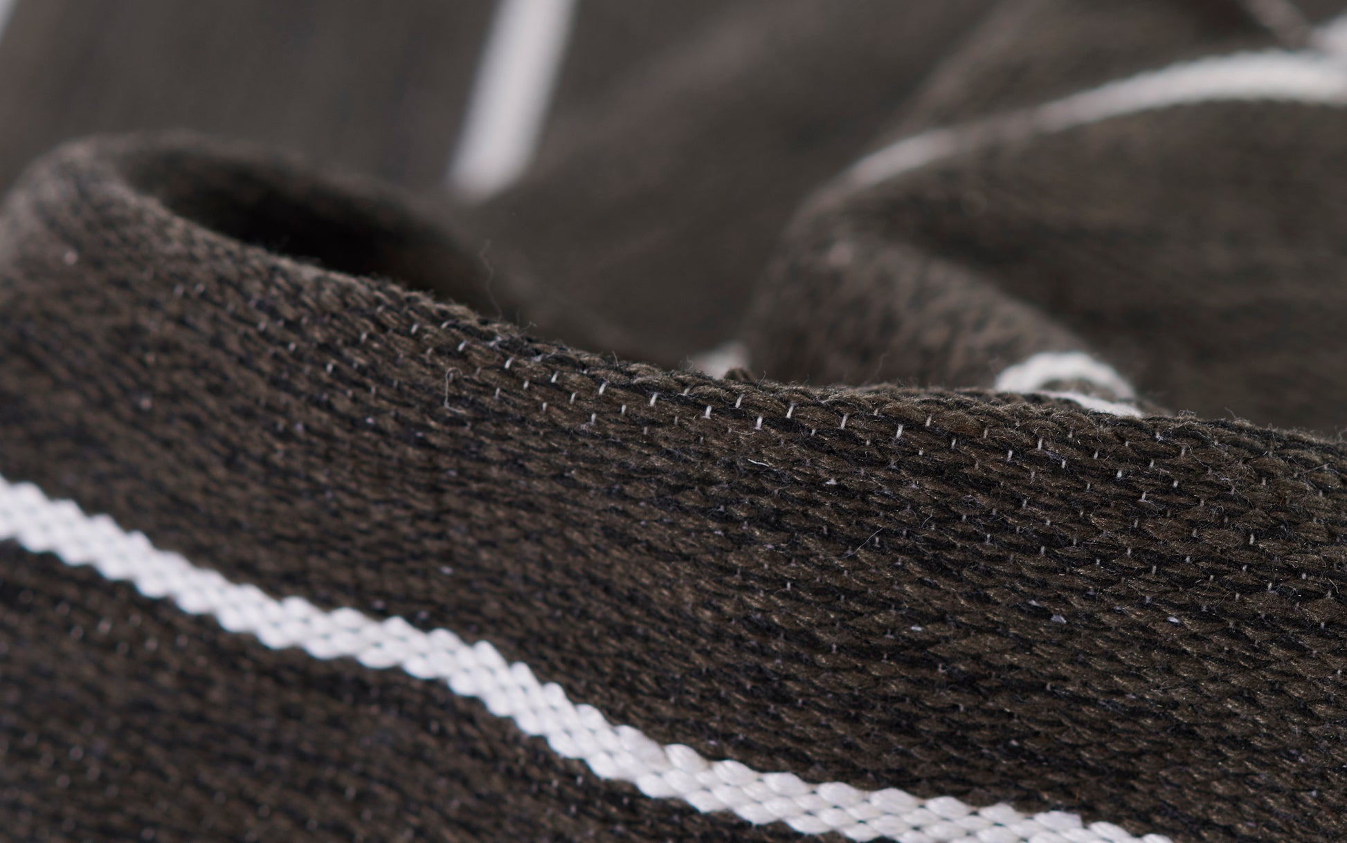 Brown knit fabric with a white stripe, close-up of stitching on a cozy sweater or scarf.