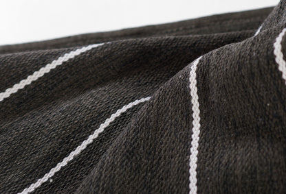 Close-up of a black rug with white pinstripes; textured, soft pile.