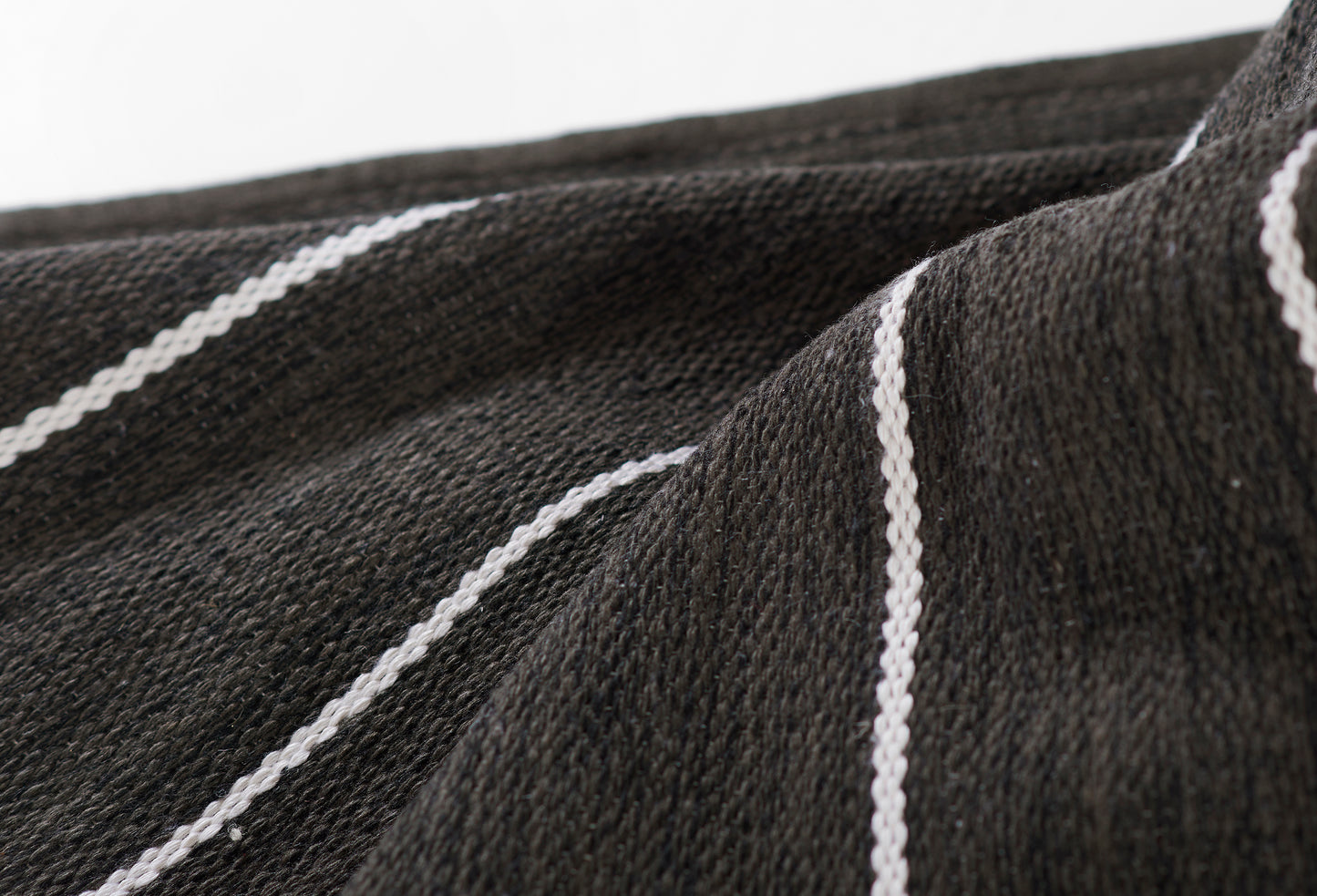 Charcoal black woven fabric with thin white diagonal stripes; textured textile suited for scarf or shawl.