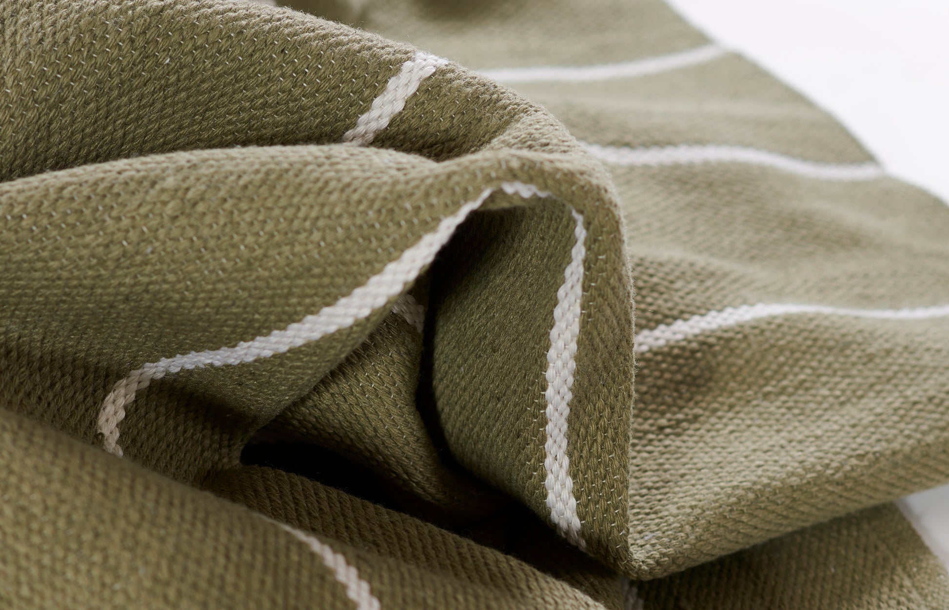 Olive green woven rug with white stripes, folded and textured.