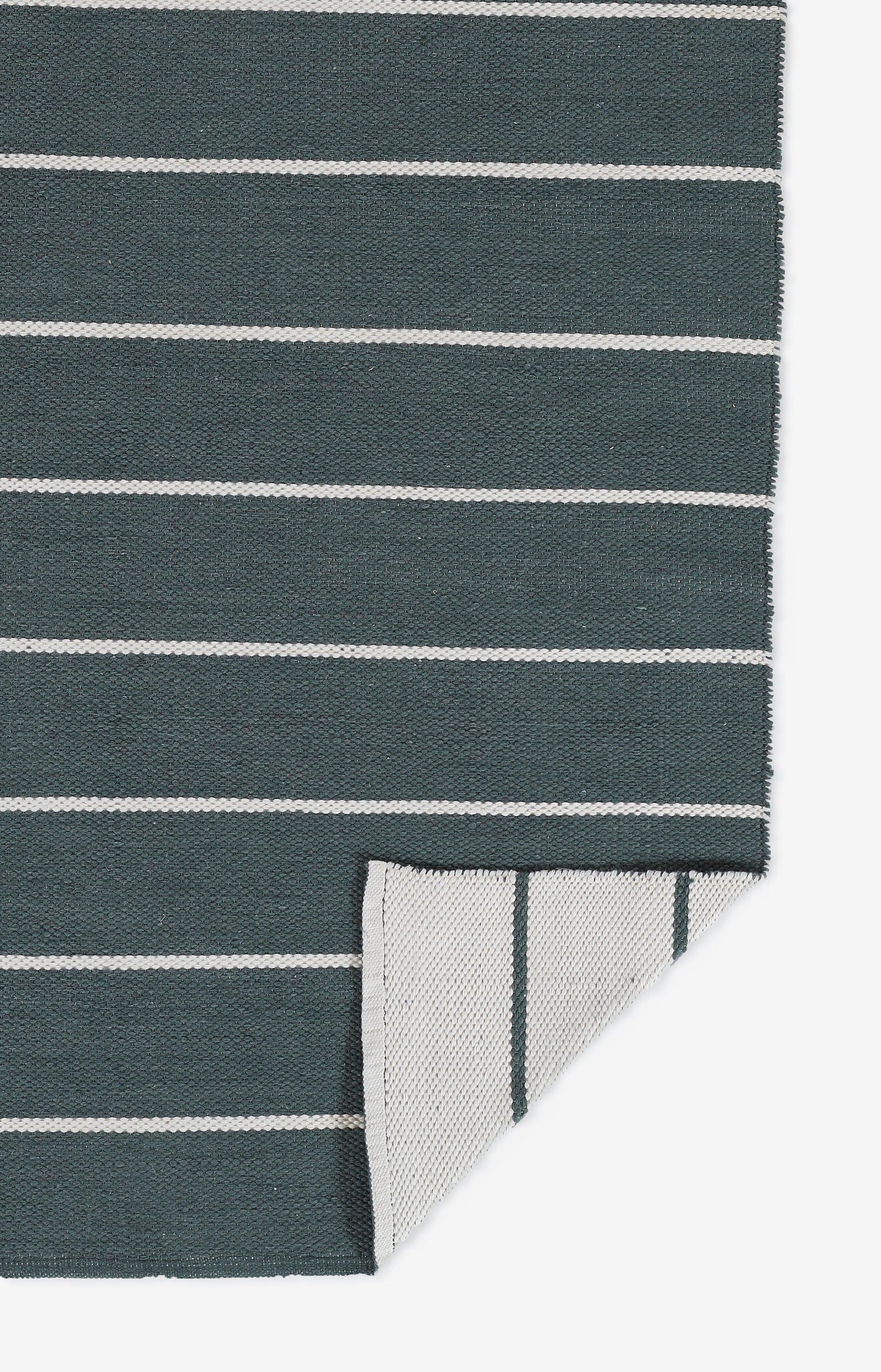 Dark teal striped textile with white horizontal bands; folded corner reveals a lighter reverse with vertical stripes.