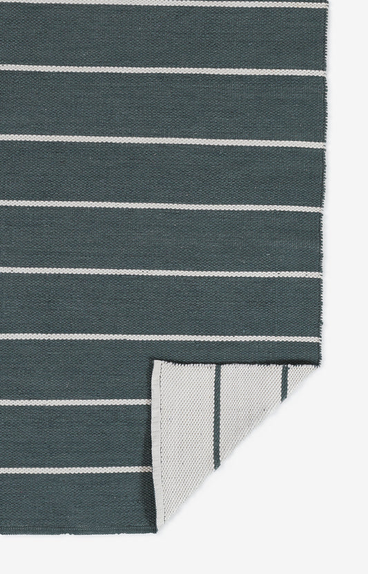 Dark teal rug with thin white horizontal stripes; folded corner reveals lighter striped underside.