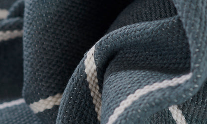 Macro shot of blue denim-like rug fabric with pale gray stripes in a textured weave.