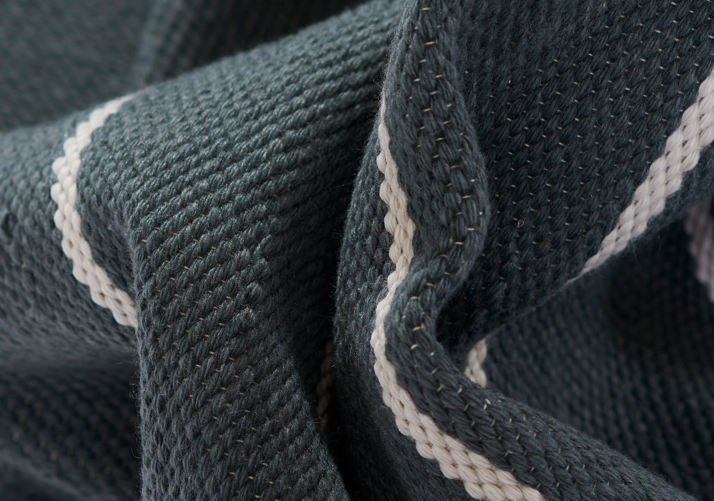 Close-up of dark navy knit fabric with a white stripe along the fold; soft, textured sweater material.