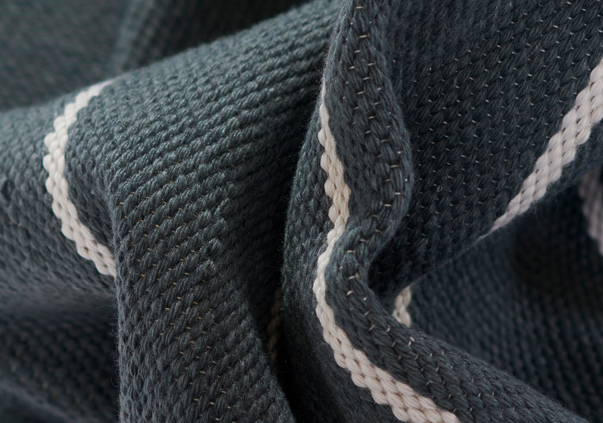 Close-up of dark navy ribbed knit fabric with a white piping stripe along the edge