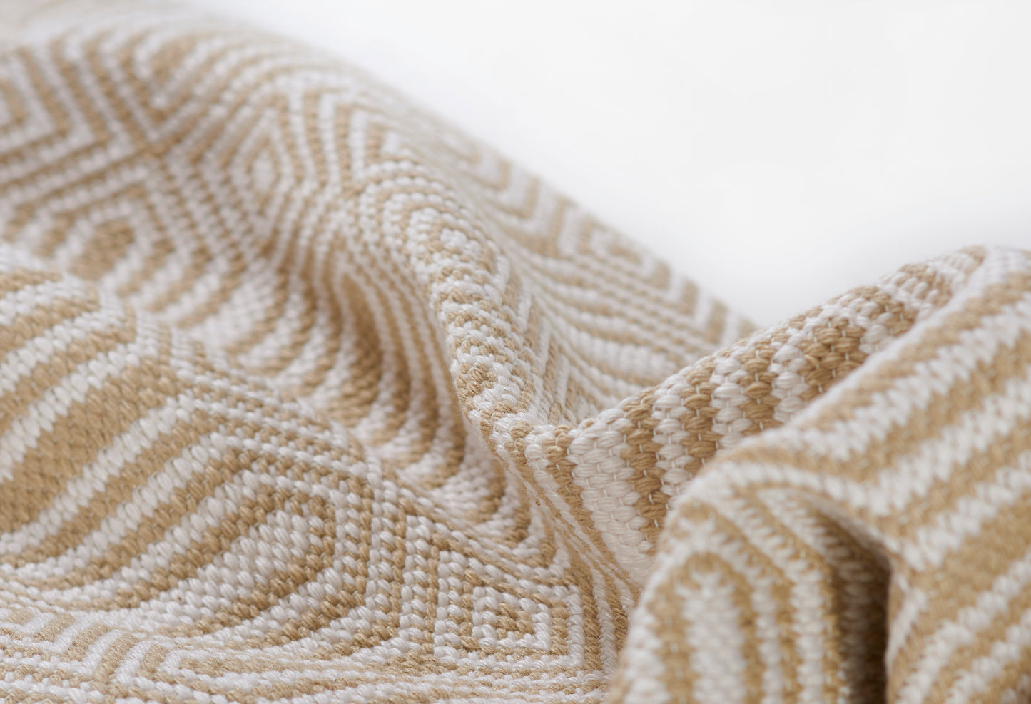 Beige and ivory woven fabric with geometric raised pattern, soft drape; ideal for throws or upholstery.