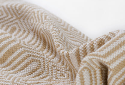 Beige and ivory woven fabric with geometric raised pattern, soft drape; ideal for throws or upholstery.