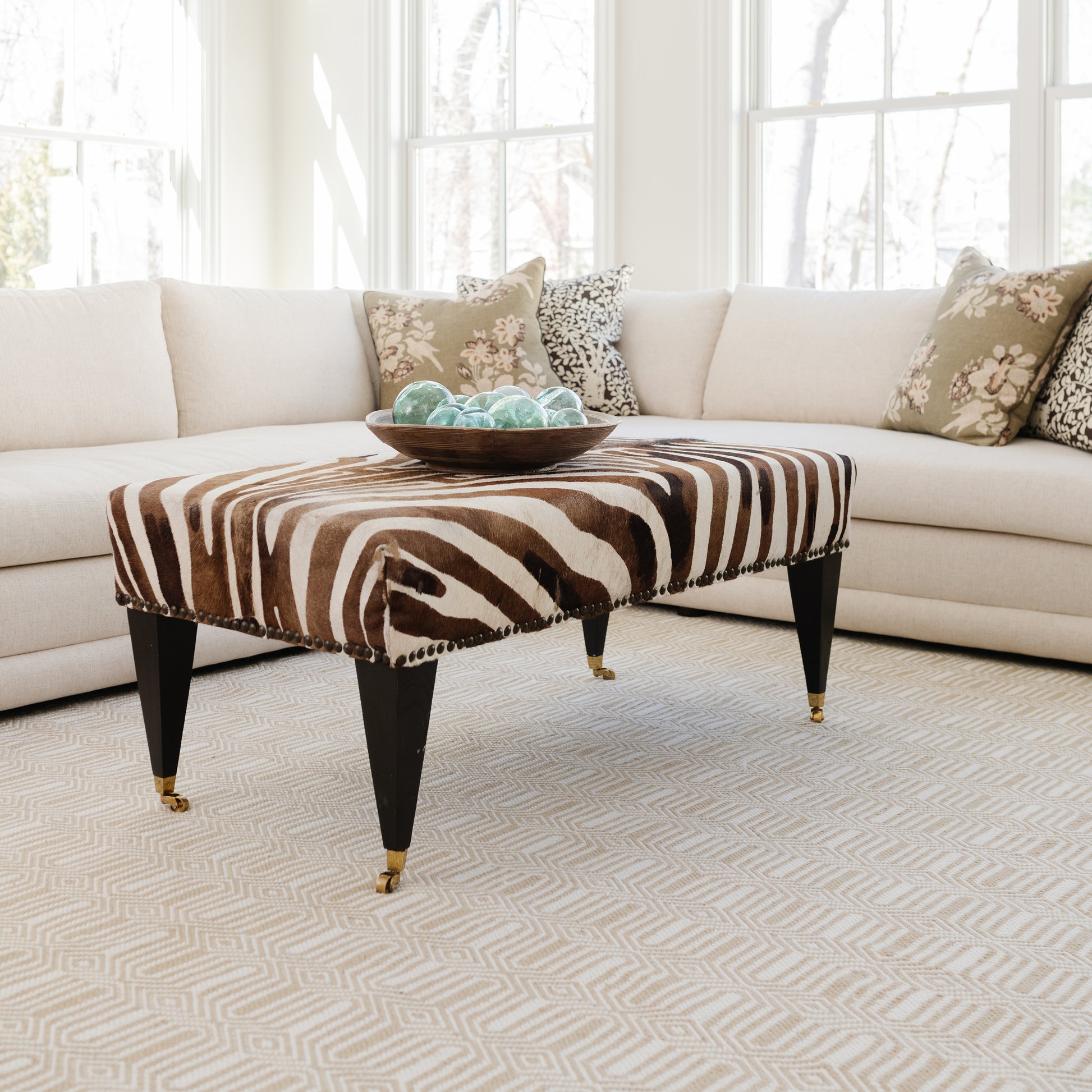 Zebra-print rectangular rug with a turquoise glass bowl on top in a bright living room.