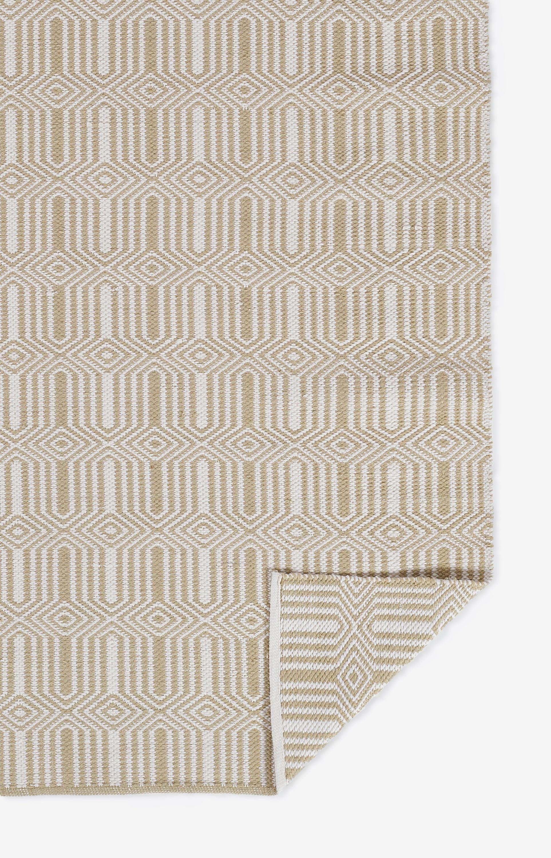 Beige woven rug with neutral taupe hexagon/diamond lattice pattern; rectangular area rug with folded corner.