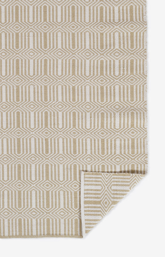 Beige geometric woven rug with interlocking diamond/hex pattern; neutral tones, rectangular with folded corner.
