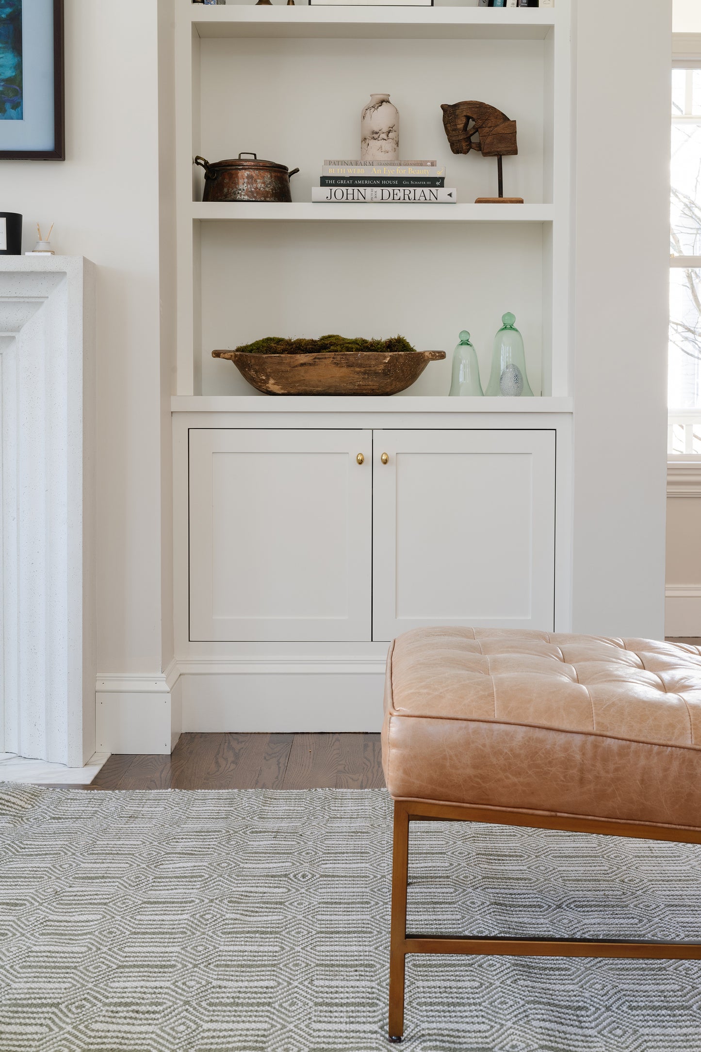 Rug on the floor in front of a white built-in cabinet with shelves.