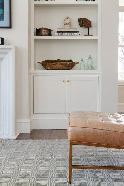 Rug on the floor in front of a white built-in cabinet with shelves.