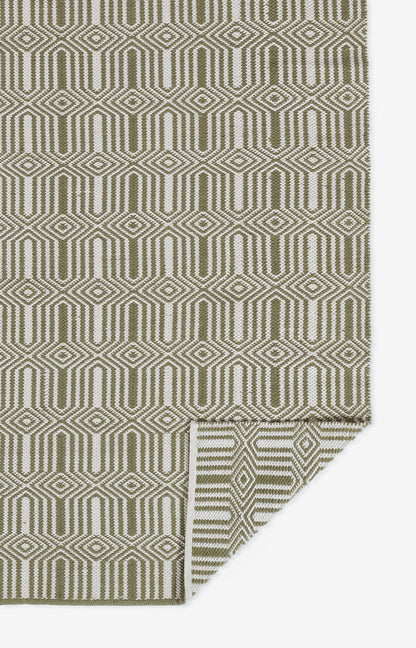 Olive green and cream geometric rug with interlocking diamond shapes; folded corner.