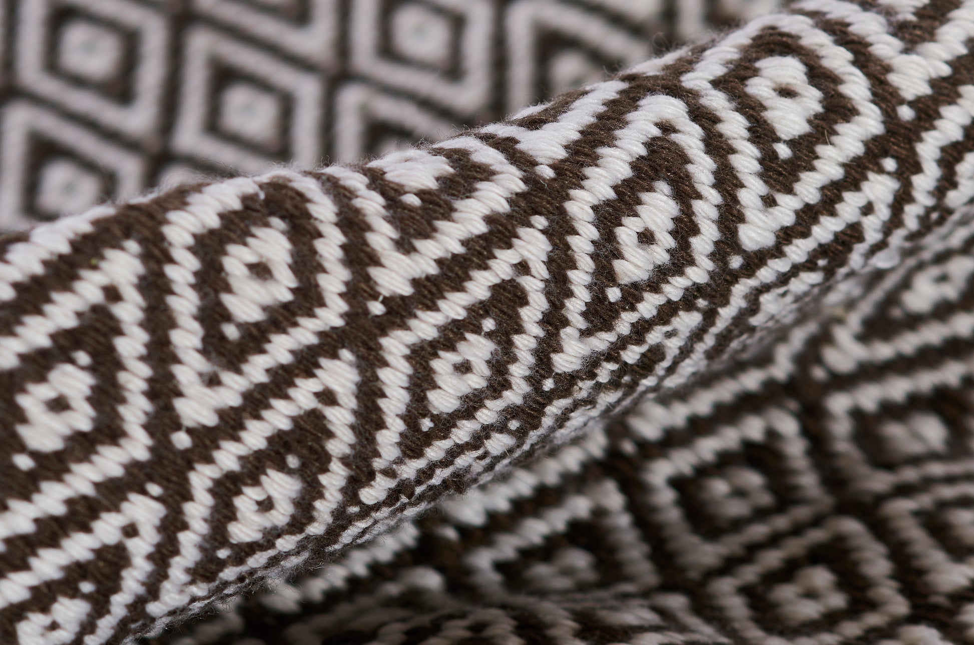 Brown and white diamond-patterned woven rug with thick pile and geometric tribal motif.