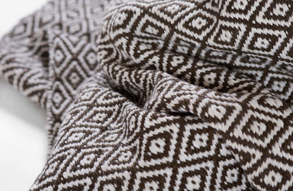 Brown and white diamond-pattern rug with a woven texture, draped in soft folds.