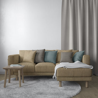 Beige fabric sectional sofa with chaise on right, teal and grey cushions, light wood legs; round coffee table, grey rug.