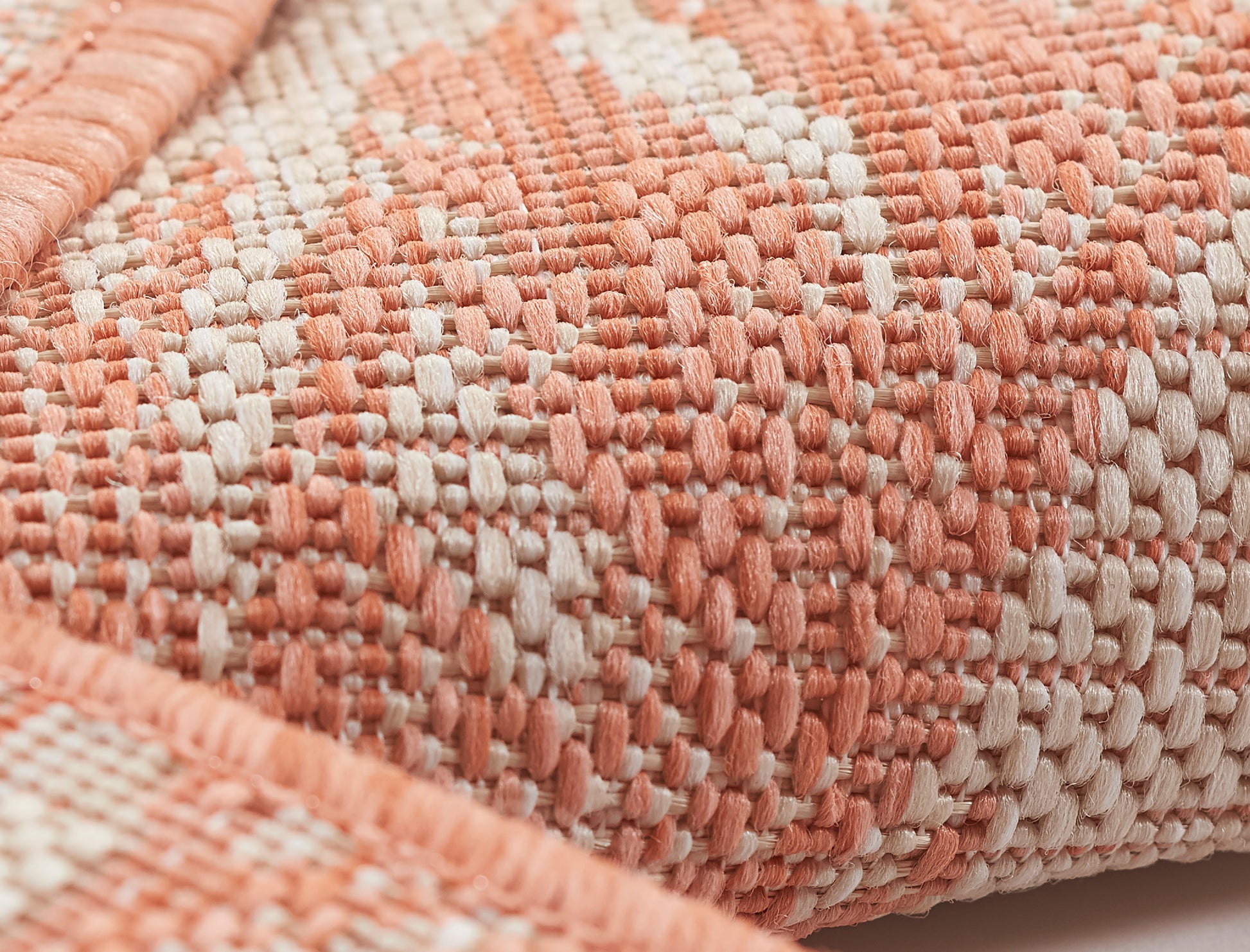 Close-up of coral and ivory woven rug with a chunky textured weave for a cozy living room look.