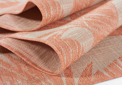 Peach-toned woven jacquard rug with a leafy damask pattern and soft folds.