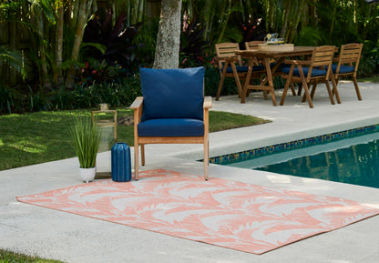 Poolside scene with peach palm-pattern rug, wooden chair with blue cushions, blue bottle, and wooden dining set.