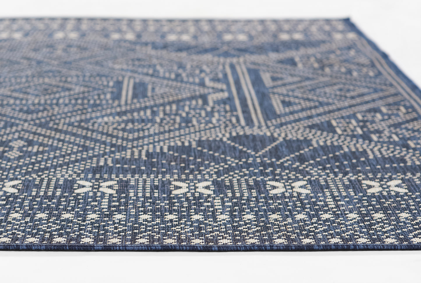 Navy blue woven rug with white geometric patterns; flat-weave rectangle for living room decor.