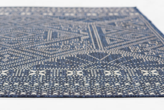 Navy blue and white flat-weave rug with geometric diamonds and chevrons; durable woven textile for living spaces.