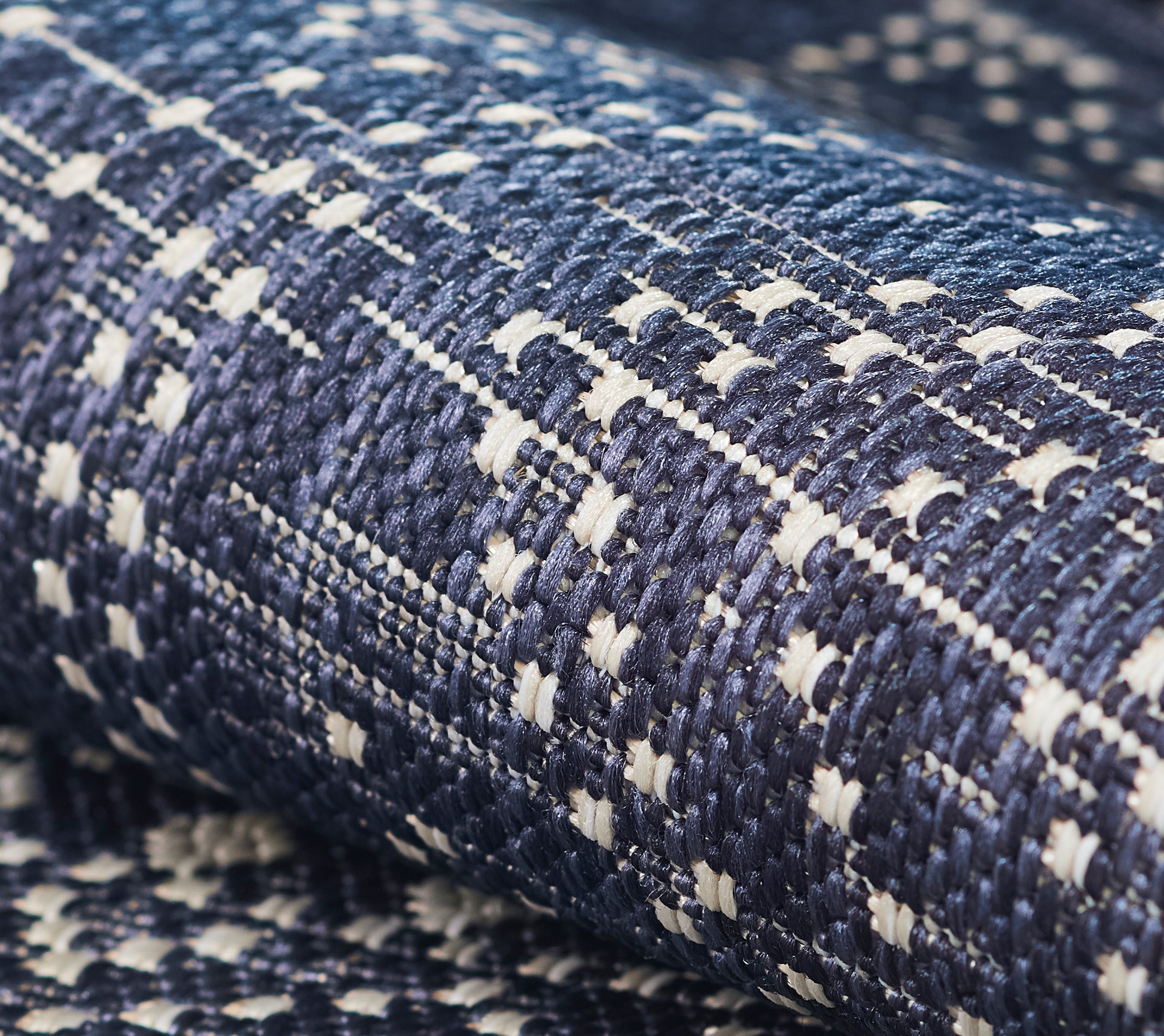 Close-up of navy blue woven tweed rug with white accents; textured surface.