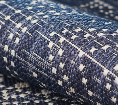 Close-up of navy blue woven tweed rug with white accents; textured surface.