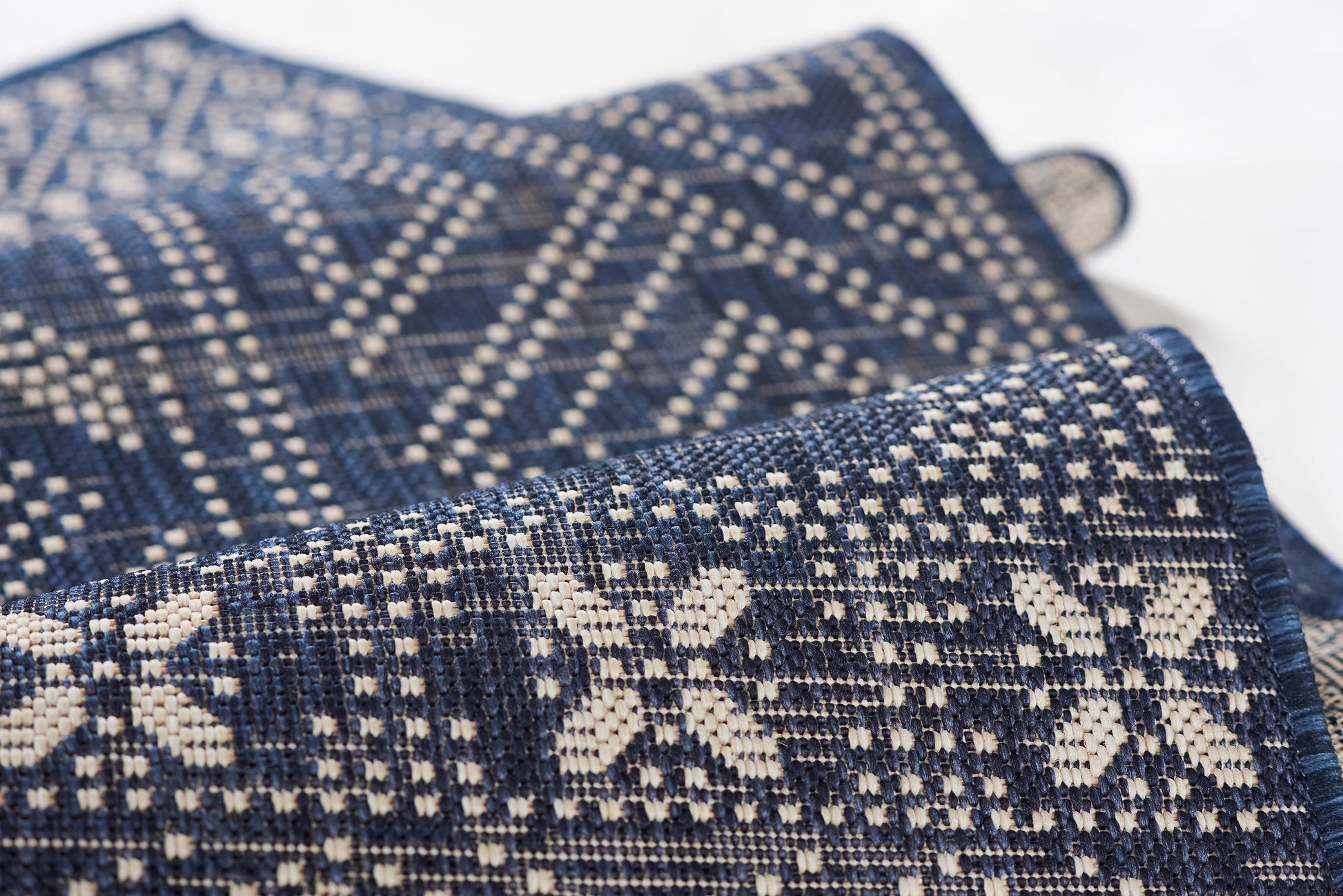 Navy blue woven throw blanket with white geometric Nordic pattern; folded, textured fabric.