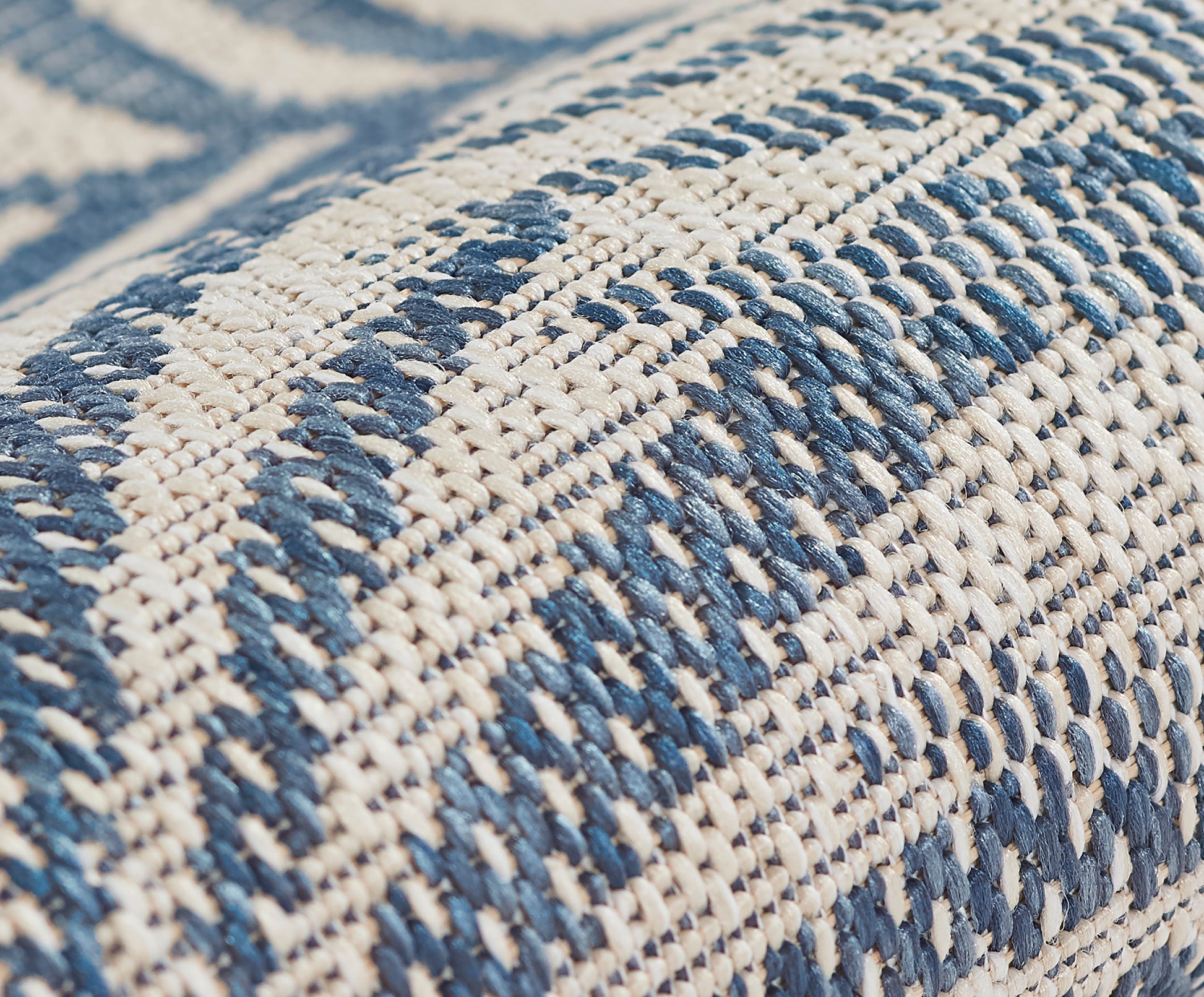 Close-up of blue & cream woven rug with braided texture and geometric stripes.