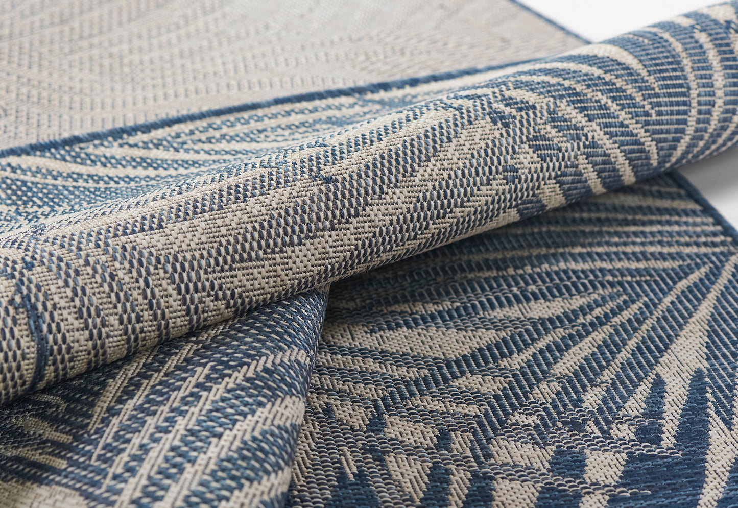 Blue and beige woven textile with geometric leaf motif, folded decorative fabric.