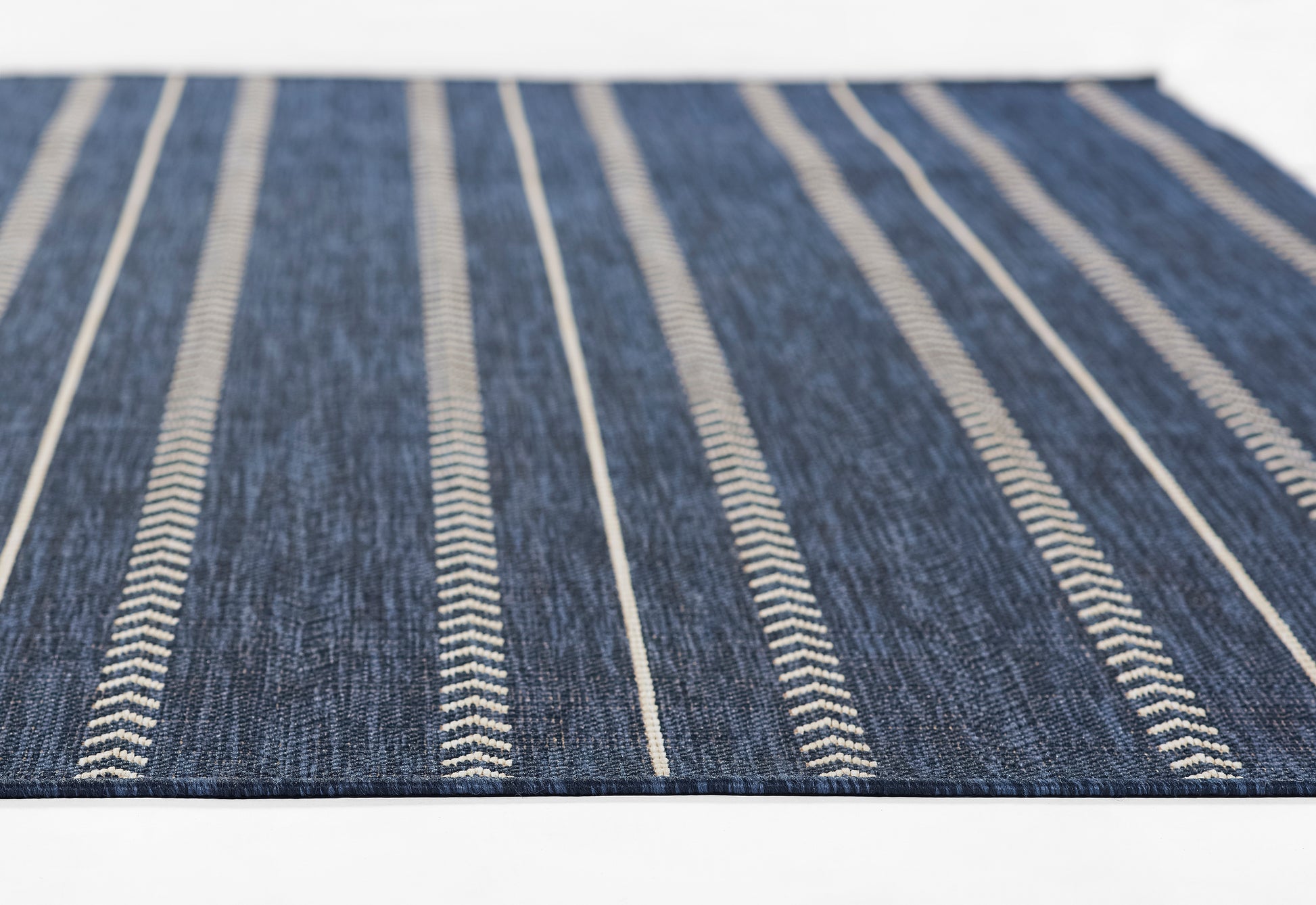 Denim blue flat-weave rug with narrow white stripes running lengthwise; casual home decor.