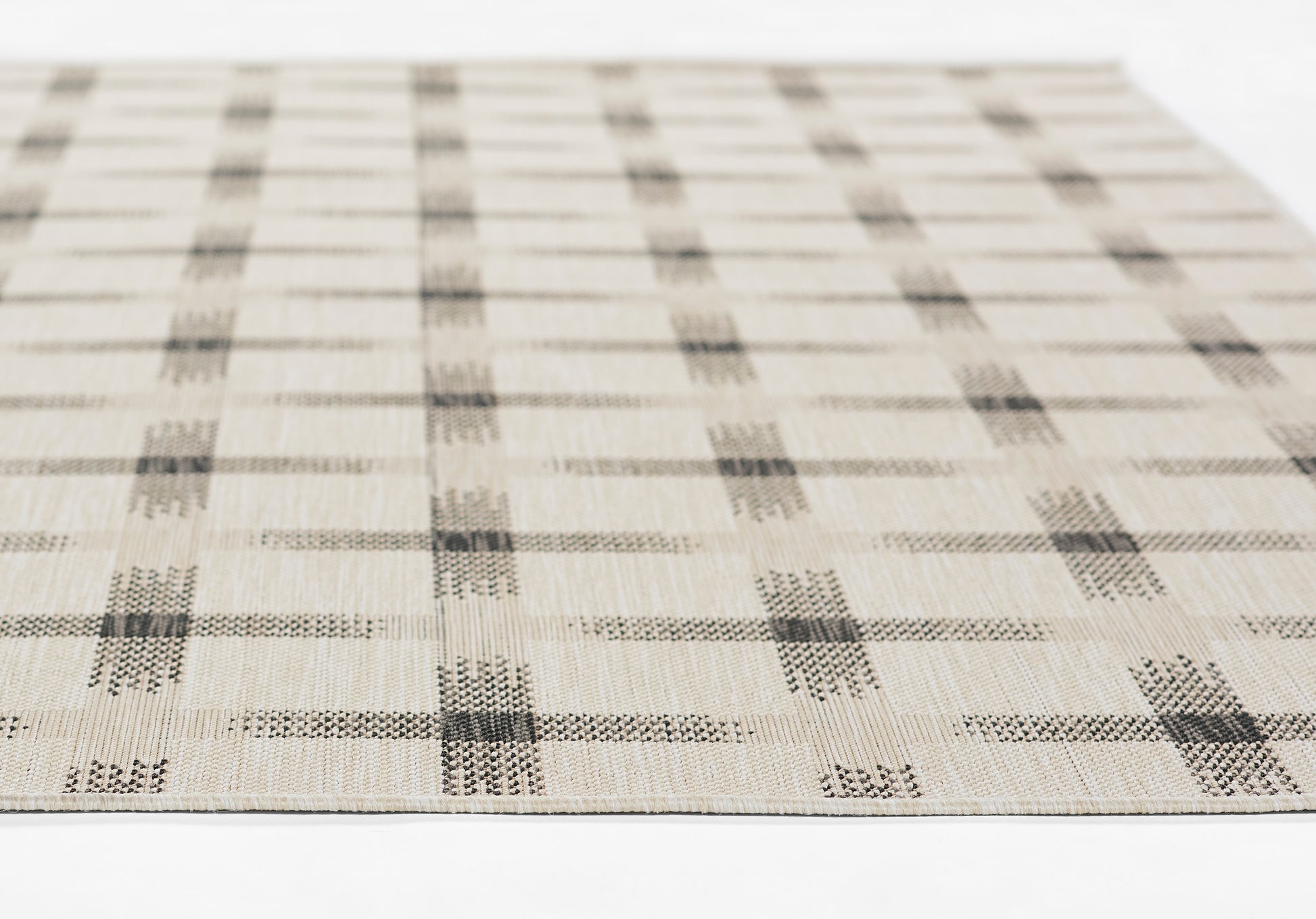 Beige woven rug with gray square grid plaid pattern, flat lay, textured surface.