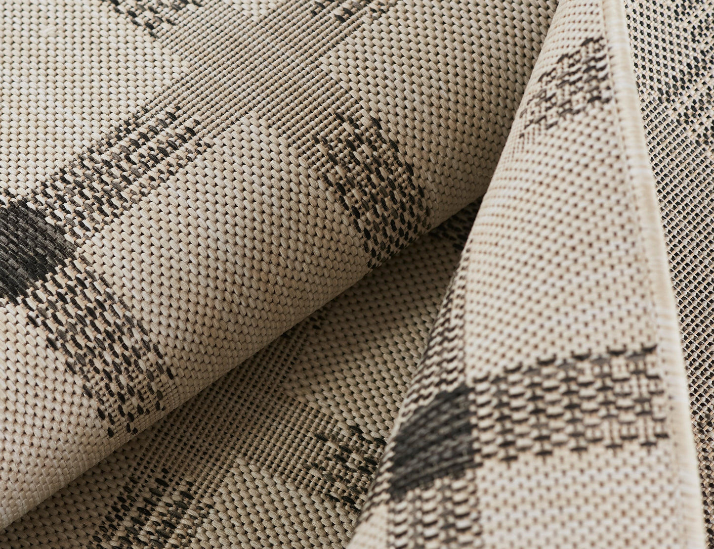 Beige woven rug with dark brown geometric diamond pattern, rolled.