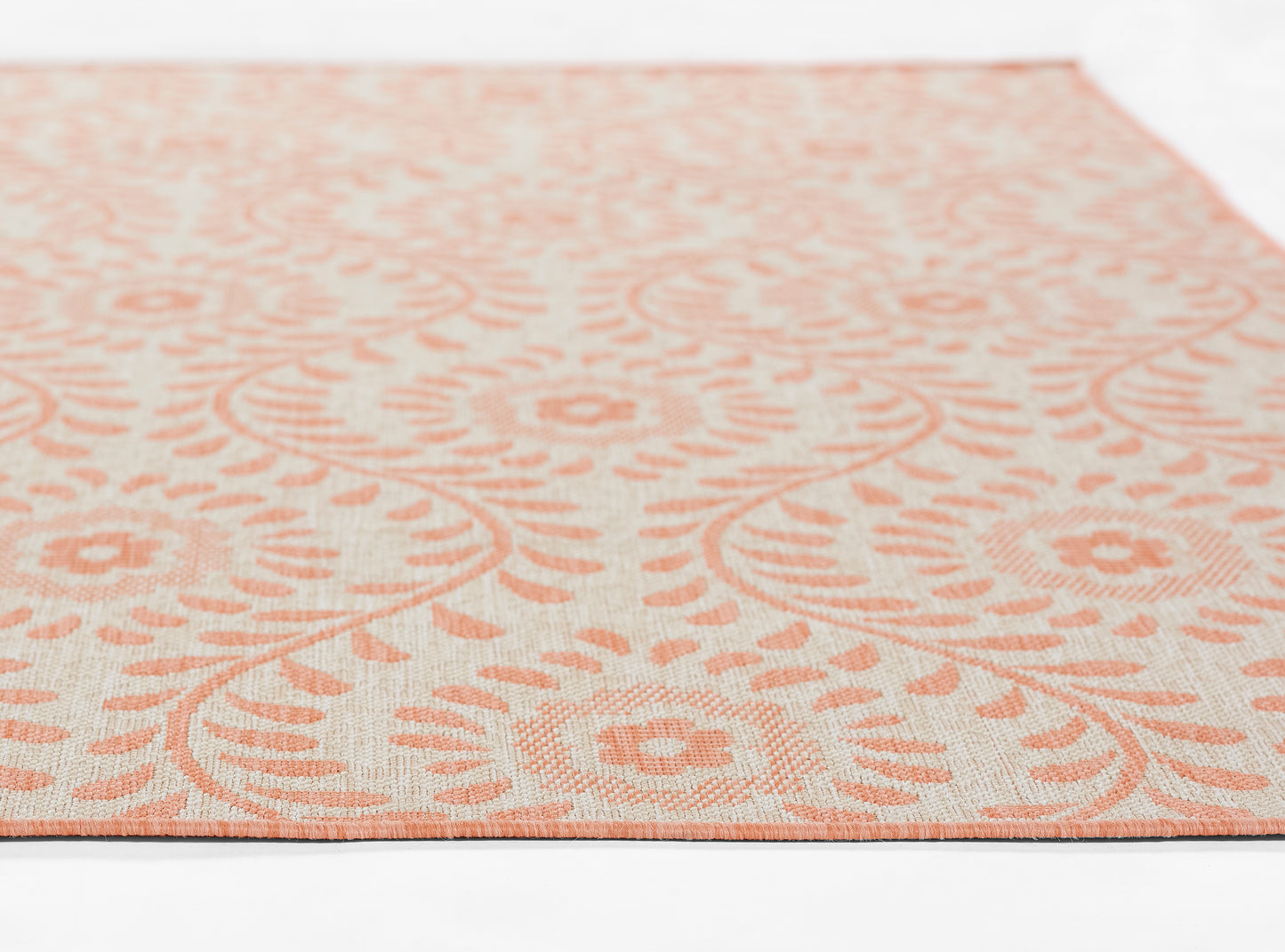 Peach floral damask area rug on cream background, flat-weave texture with a dark border, ideal for living room decor.