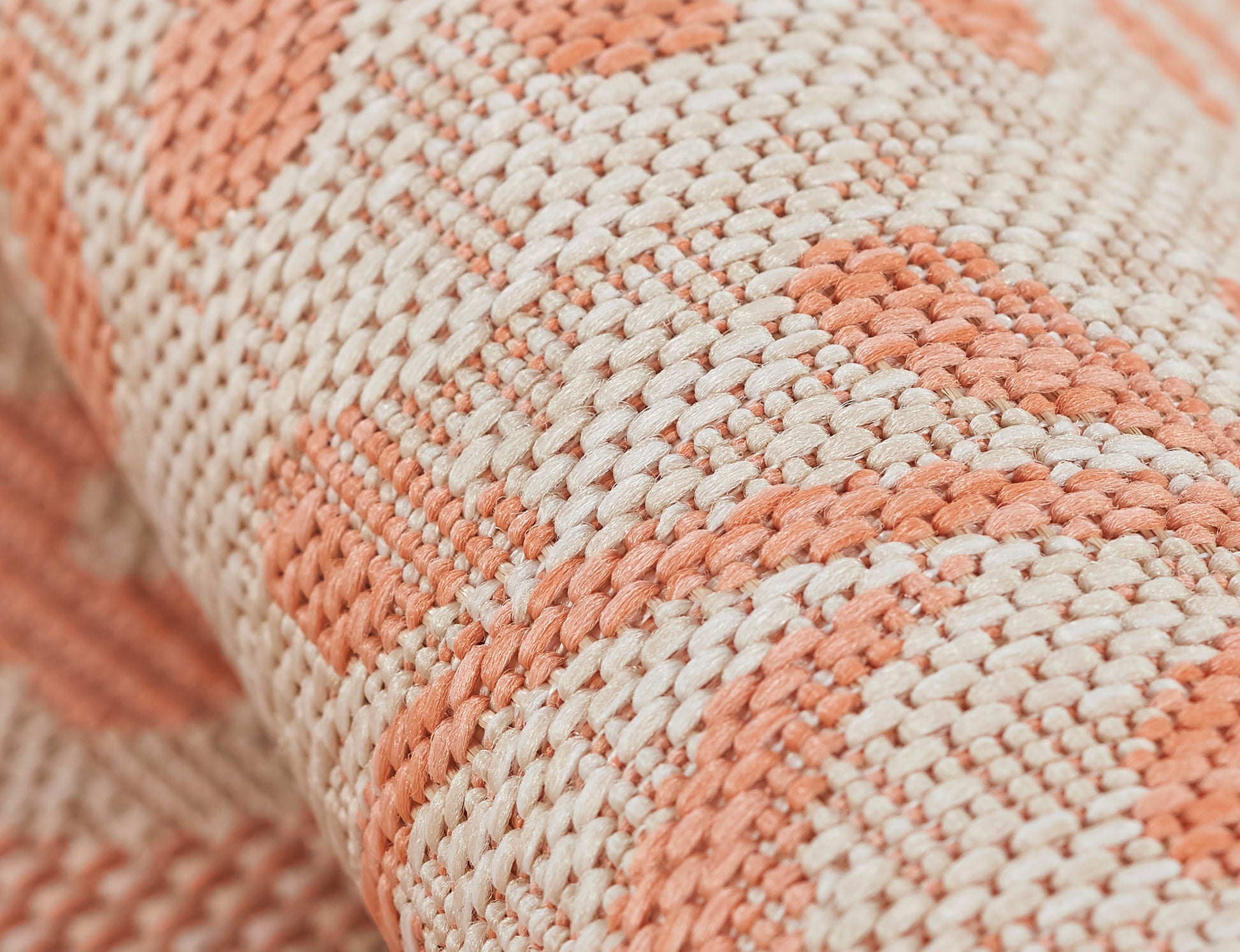 Close-up of peach and cream woven rug with chunky yarn and geometric stripe pattern.