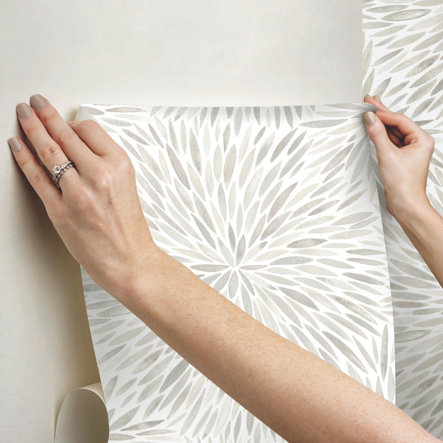 Hands hold a sheet of gray starburst wallpaper; modern geometric print for walls.