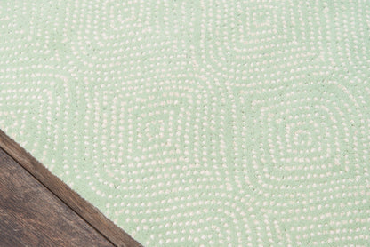 Mint green rug with cream dotted geometric maze pattern; soft texture near wood floor corner.
