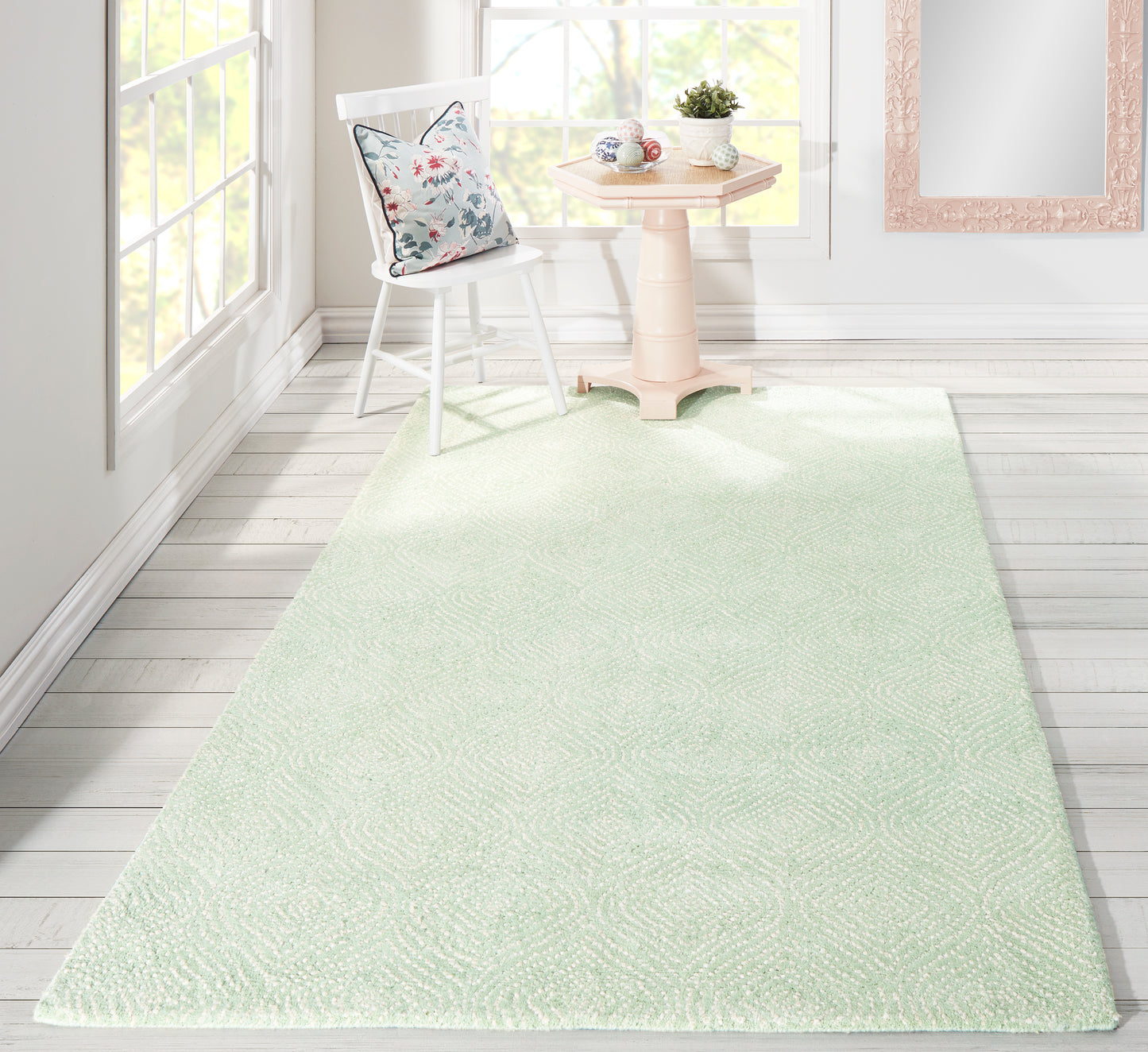 Mint green textured runner rug on white wood floor; bright room with floral cushion chair & pink pedestal table.