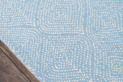 Blue rug with a white dotted geometric swirl pattern on a wooden floor