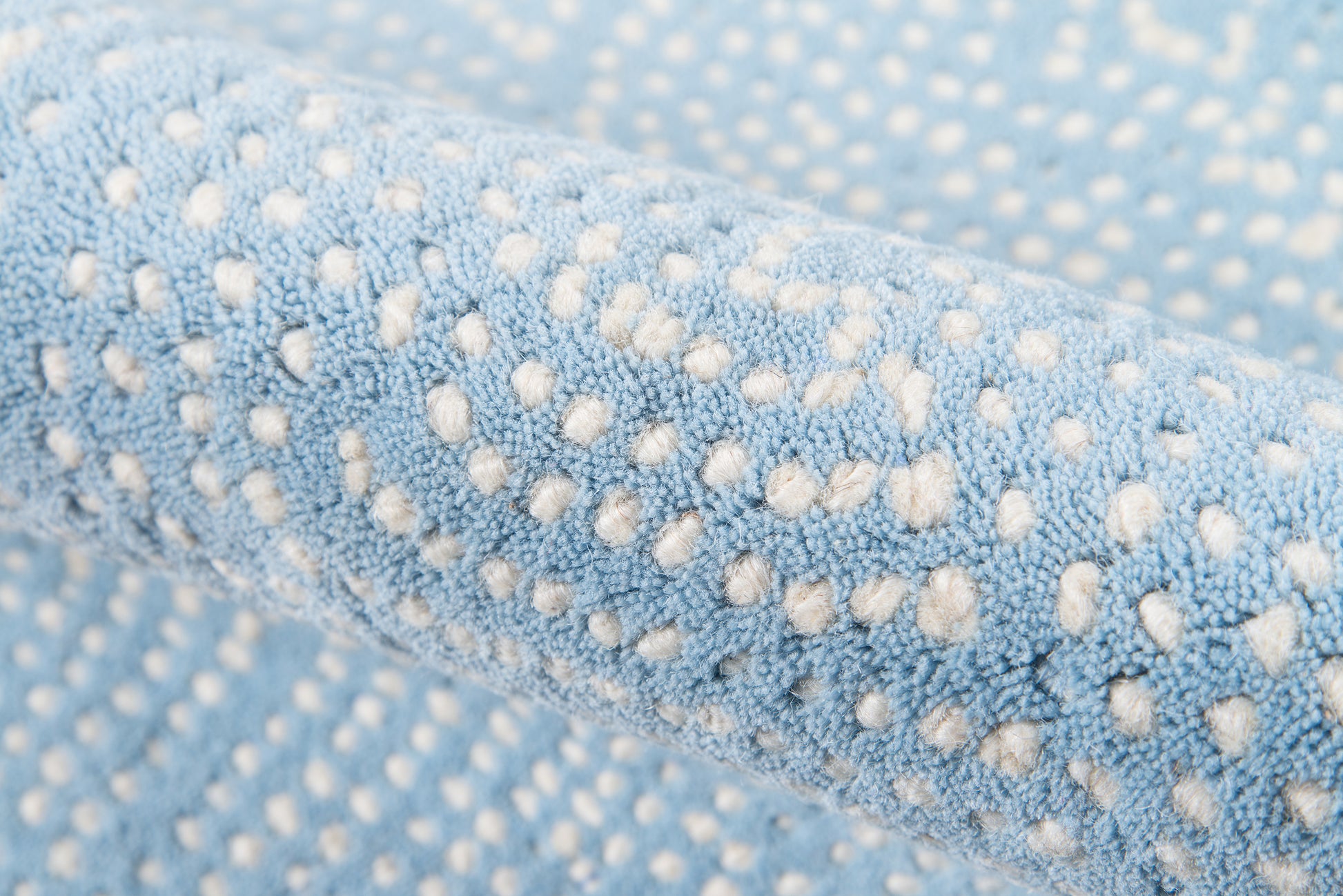 Close-up of light blue plush microfiber fabric with white raised dot pattern, soft and cozy.