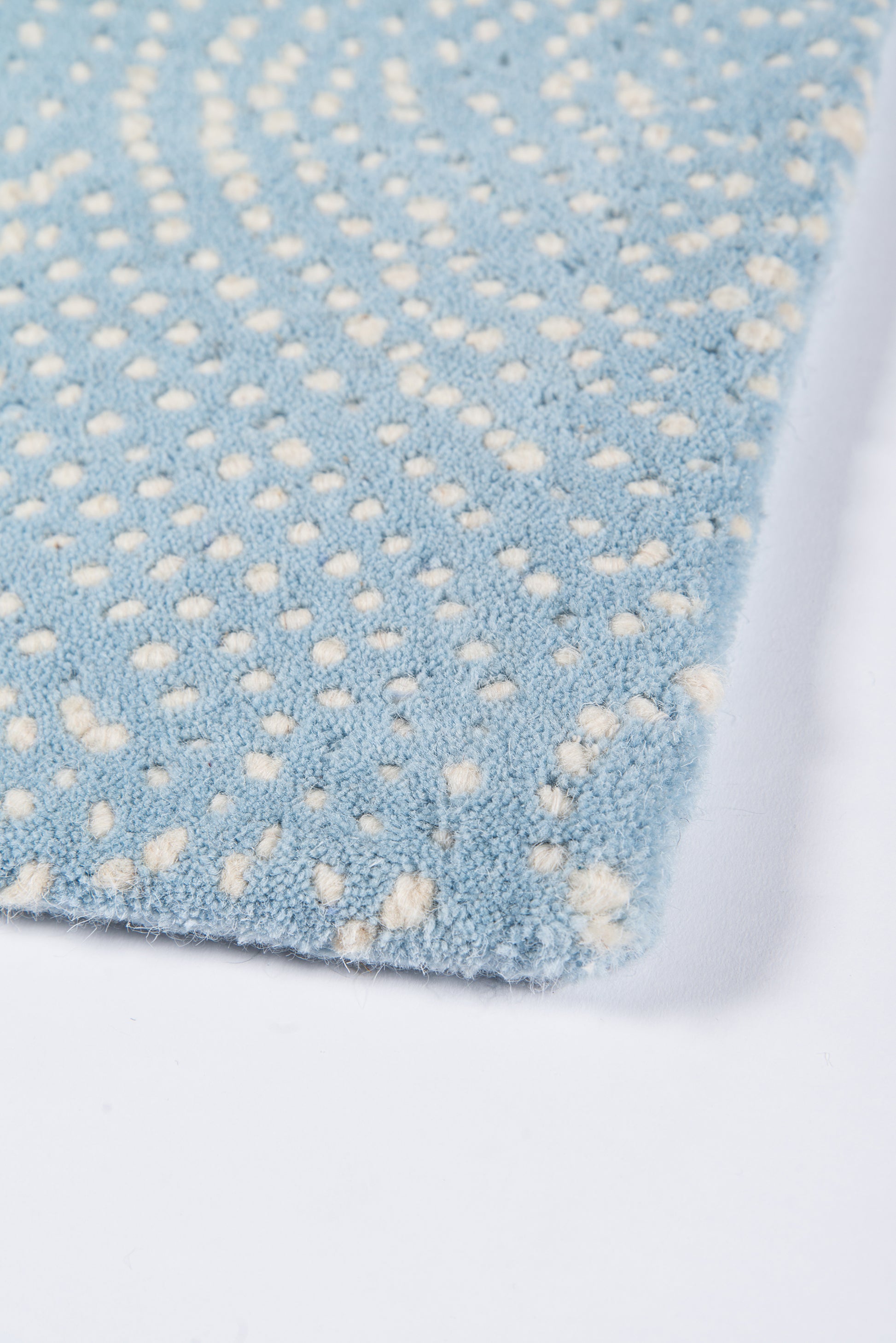 Soft blue shag rug with cream dot pattern; plush microfiber texture, corner view.