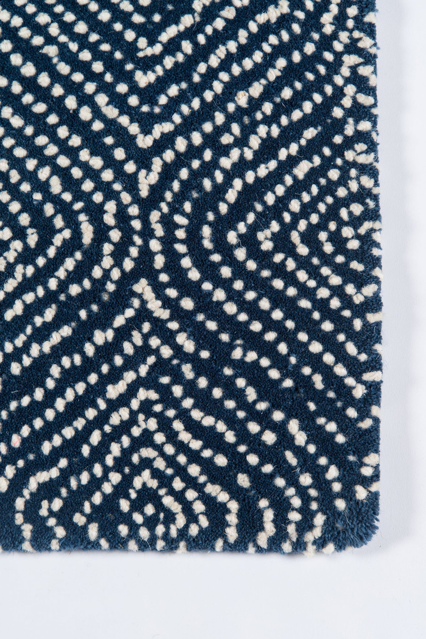 Navy rug with white dotted geometric motif and fringed edges; plush, contemporary.