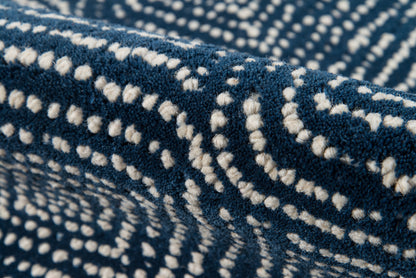 Navy blue tufted rug with white dotted swirl pattern; plush looped yarn for cozy texture.