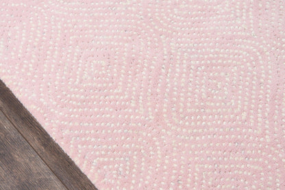 Pink textured rug with white dotted geometric maze pattern on wooden floor.