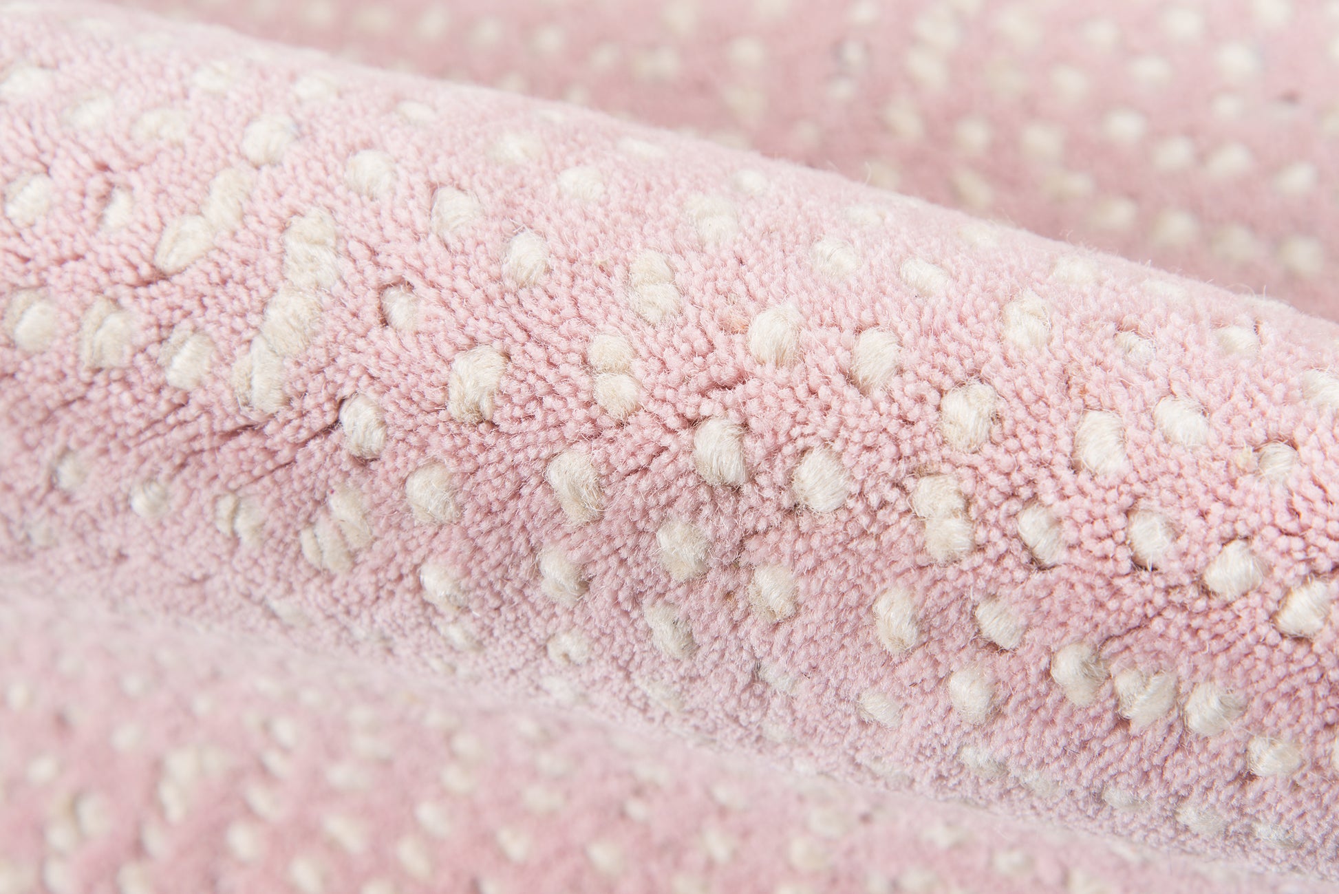 Soft pink plush rug with white raised dot tufting; cozy textured material.