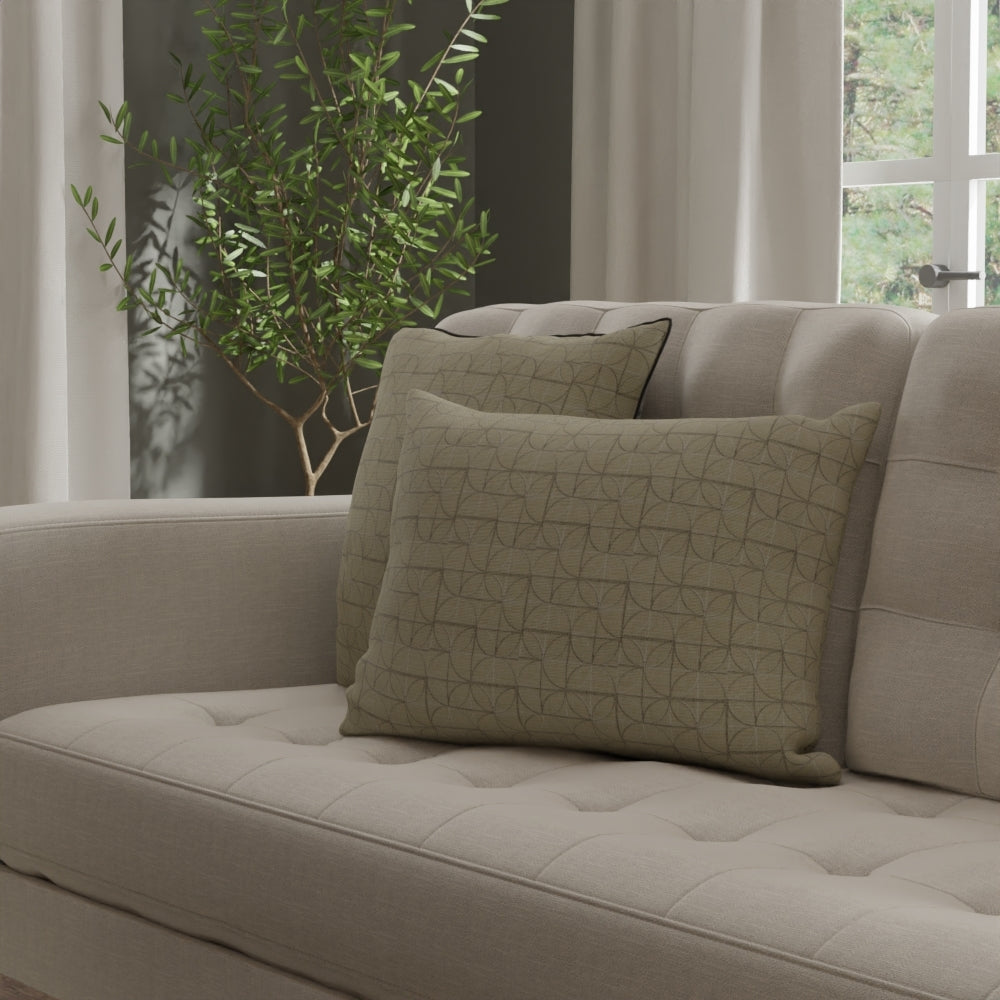Beige tufted sofa upholstered in Limestone Geometric Fabric with two geometric-pattern cushions in a neutral living room with a potted plant
