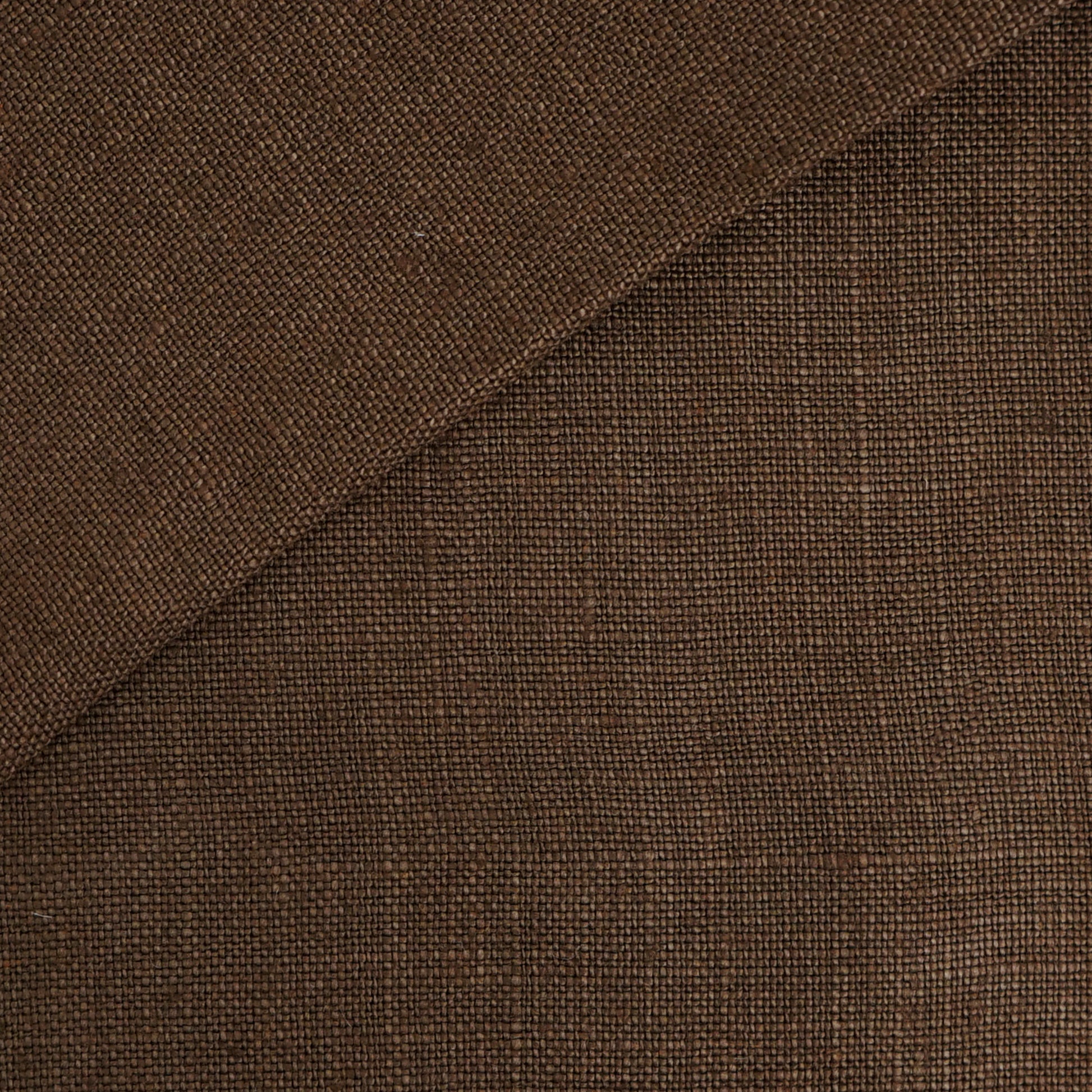 Brown linen fabric close-up with visible texture, diagonal seam, folded edge.