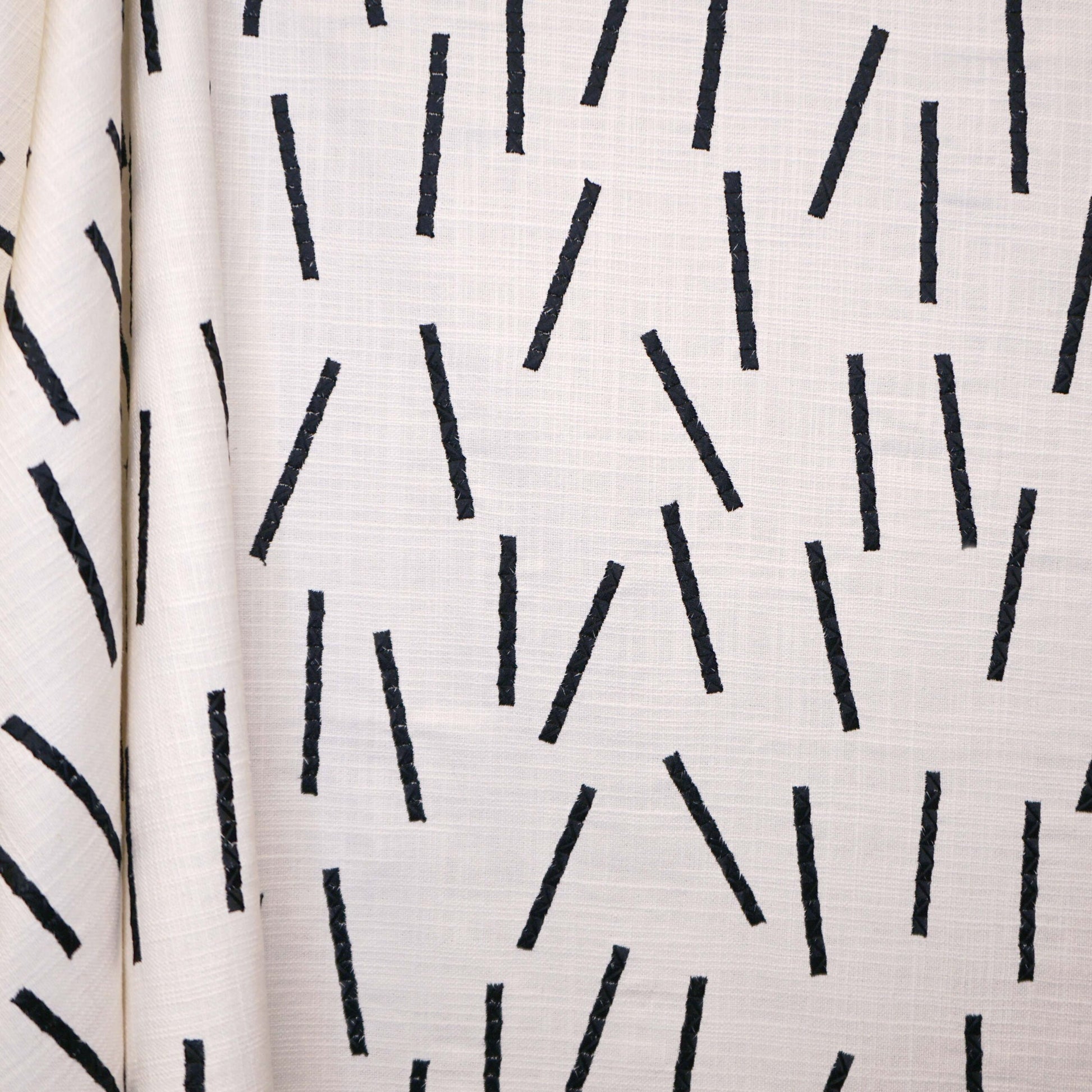 Cream linen fabric with thin black diagonal lines and visible weave.