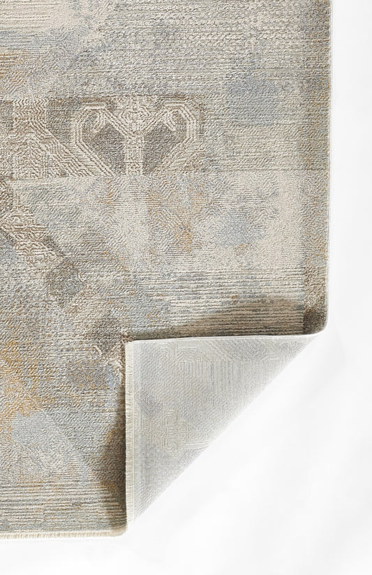 beige-gray patterned rug with damask motif, textured weave, folded corner showing light backing